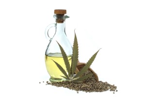 Hemp (Cannabis sativa) leaf in front of cannabis oil in glass decanter and hemp seeds isolated on