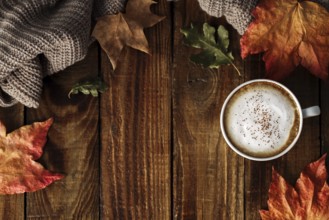 Hot coffee cappuccino, blanket and autumn leaves on old wooden background. Vintage toning. Seasonal