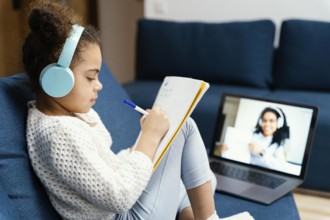Side view little girl during online school with laptop headphones