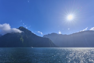 Bright sun over mountains and an expanse of water, summer, Milford Sound, Te Anau, Fiordland