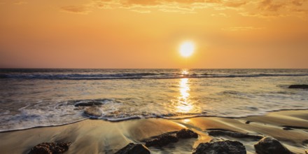 Tropical beach vacation background, panorama of waves and rocks on beach on sunset with beautiful