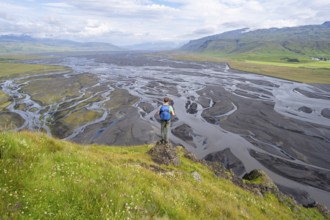 Hiker, young man on a hill, view over alluvial land, meandering river, Dímonarhellir, Suðurland,