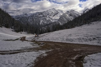 Picturesque view of snow-covered mountains on a path in front of dramatic clouds, Krün, Bavaria,