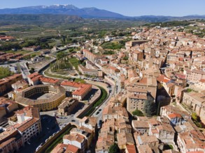 Aerial view of a historic town with tiled roofs and a hilly landscape in the background, aerial