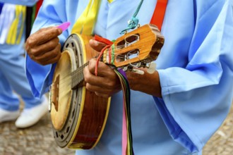 Hands of banjoist on the streets of Brazil wearing colorful clothes during a traditional religious