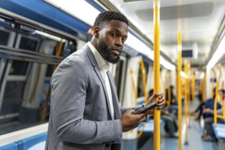 Young businessman commuting on a subway train, using a smartphone for browsing social media and