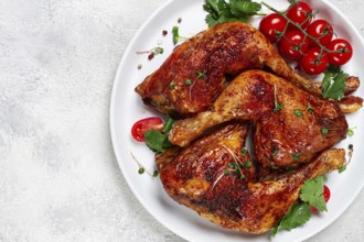 Grilled fried chicken legs, served, with fresh cherry tomatoes, and herbs, on a white plate,