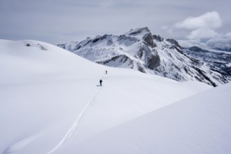 Two lonely ski tourers in a snow-covered mountain landscape, mountain peak Sex des Molettes in the