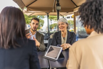 Business team talking and using digital tablet during meeting in a cafeteria