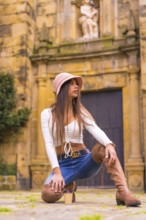A young Latin woman with a white t-shirt, jeans and a hat enjoying the summer holidays, with a take