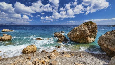 Stony beach with large rocks and gentle waves under a blue sky, Kato Lakkos Beach, still almost