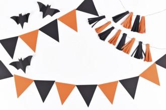 Halloween background with garlands and paper bats in traditional colors orange and black on white