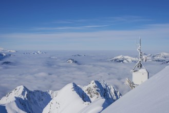 Mountain panorama in winter, snow-covered mountain peaks rise above cloud cover, view from