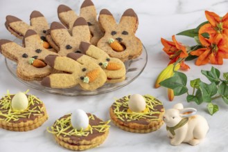 Bunny biscuits with carrots and egg decoration next to orange flowers and Easter bunny