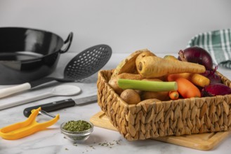 A basket full of different vegetables with kitchen utensils in preparation for cooking