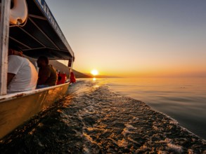 View from below along the orange sunset water of Shkoder Lake in Shiroka from a tourist boat.