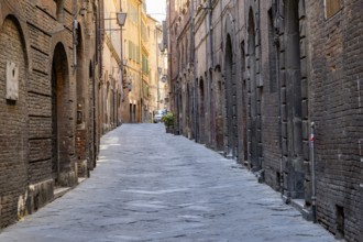 View of a small street going through old buildings in the city of Siena, Tuscany, Italy, Europe