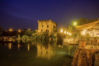 Night shot of restaurant on the Mincio river and Visconti bridge from 1395 in the background,