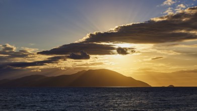 A sunset with rays bathing the sea and an island in a golden hue, sunset, Kassos, Karpathos,