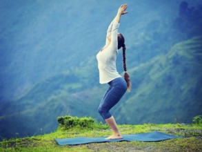 Young sporty fit woman doing yoga asana Utkatasana (chair pose) outdoors in mountains Himalayas in