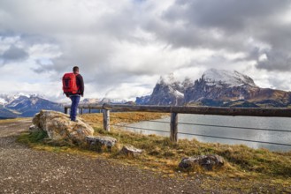 Hiker standing on stone, Sassopiatto, Sassolungo, Dolomites, Alpe di Siusi, lake, snow, clouds,