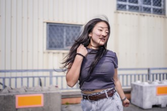 Three quarter length photo of a young cool asian girl dancing k-pop outdoors in an industrial