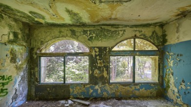 Dilapidated arched windows in an abandoned building with traces of decay and blue walls, Lost