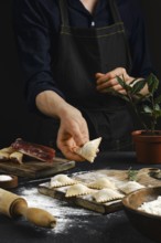 A person in an apron carefully shapes filled pasta in a warmly lit kitchen. Flour dust covers the