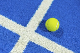 Paddle tennis yellow ball in a blue court with white lines