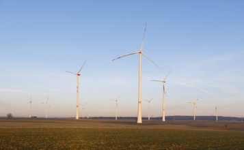 Large wind turbines spread across an open field landscape under a bright sky, solar park, near Ulm,