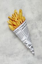 Fried French fries in a paper bag, on an abstract background, without people, in a rustic style, in