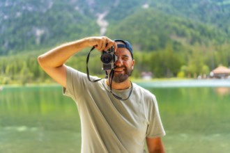 Tourist taking pictures with vintage camera at lake dobbiaco, surrounded by the breathtaking