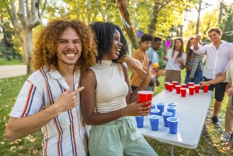 Man pointing at a female african friend that wins playing beer pong at park