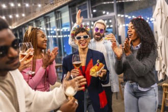 Happy woman celebrating birthday with multiracial friends at bar in the night