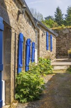 Narrow alley in an old idyllic French villages with picturesque stone houses and blue window