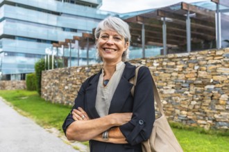 Portrait of a smiling mature businesswoman standing proud with arms crossed outdoors in a financial