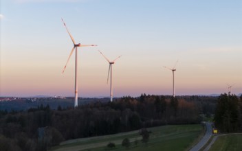Wind turbines on a road at dusk with forested background, Rems Valley, Baden-Württemberg, Germany,