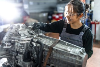 Asian woman mechanic working diligently on a vehicle gearbox in a professional garage, showcasing