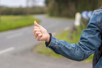 Close-up photo of the hand of a woman hitchhiking in a rural road