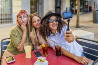 Latin beauty Woman recording video with camera while sitting with friends on a terrace drinking