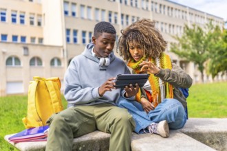 Young and multiracial university students using digital tablet studying outside the campus
