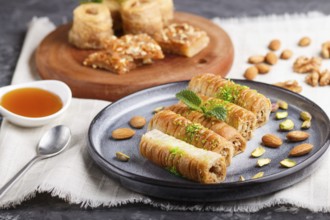 Set of various traditional arabic sweets: baklava, kunafa, basbus in ceramic plates on a gray