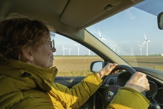 Woman driving a car, wind turbines, Reußenköge, North Frisia, Schleswig-Holstein, Germany, Europe