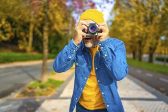 Surprised modern mature man tourist photographing in the city street during fall