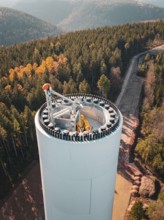 Autumn landscape with a wind turbine under construction, surrounded by colourful forest and