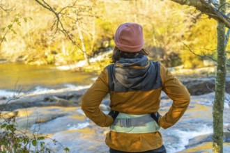 Hiker admiring the serene zaldibartxo pool in gorbeia natural park on a sunny autumn day,