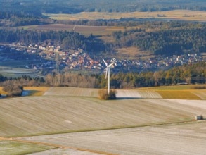 A wind turbine stands in a frosty landscape with a village in the background, district of Calw,