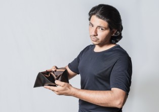 Bankrupt person showing an empty wallet isolated. Unhappy young man with financial crisis