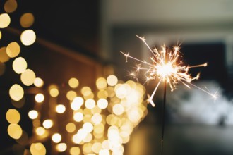 Sparklers on blurred christmas lights. Festive mood.