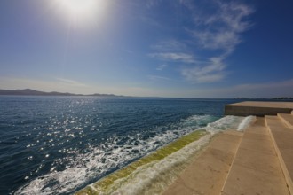 Steps lead to the clear sea under bright sunshine and blue sky, a calm coastal atmosphere, sea